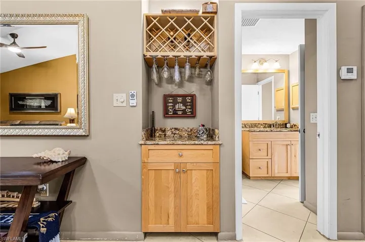 Bar featuring light stone countertops, light tile patterned floors, light brown cabinetry, and a ceiling fan