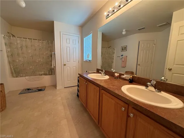 Full bathroom with double vanity and a shower with shower curtain