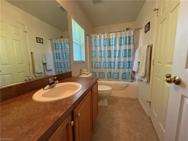 Bathroom with vanity, shower / bath combo with shower curtain, and tile patterned floors