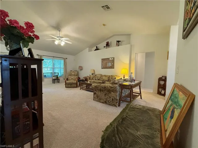 Living area featuring ceiling fan, carpet, and lofted ceiling