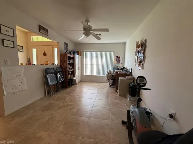 Living room featuring vaulted ceiling, light carpet, ceiling fan, and light tile patterned floors