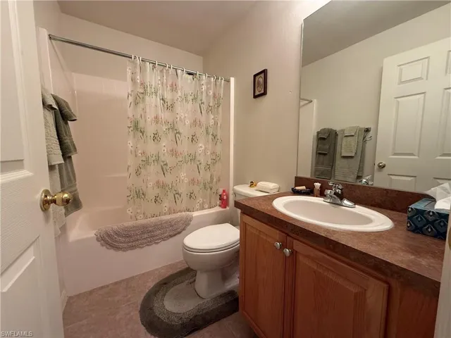 Bathroom with vanity, shower / bath combo with shower curtain, and tile patterned floors