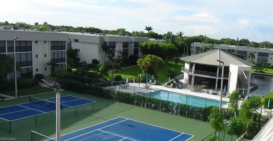 View of tennis court with a community pool