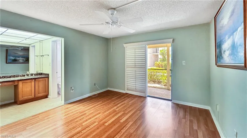 Unfurnished bedroom with ceiling fan, access to outside, a textured ceiling, and light hardwood / wood-style flooring