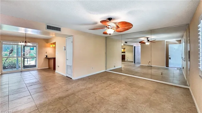 Tiled spare room featuring ceiling fan with notable chandelier and a textured ceiling