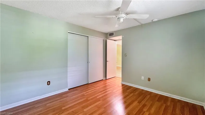 Unfurnished bedroom featuring a textured ceiling, ceiling fan, wood-type flooring, and a closet