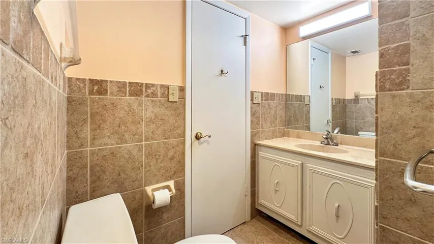 Bathroom with vanity, tile patterned flooring, toilet, and tile walls