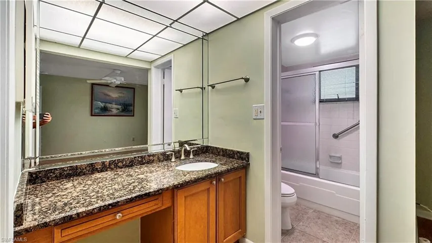 Full bathroom with shower / bath combination with glass door, vanity, tile patterned floors, and toilet
