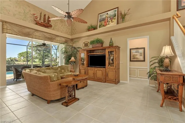 Living room featuring high vaulted ceiling, a sunroom, light tile patterned flooring, and a ceiling fan