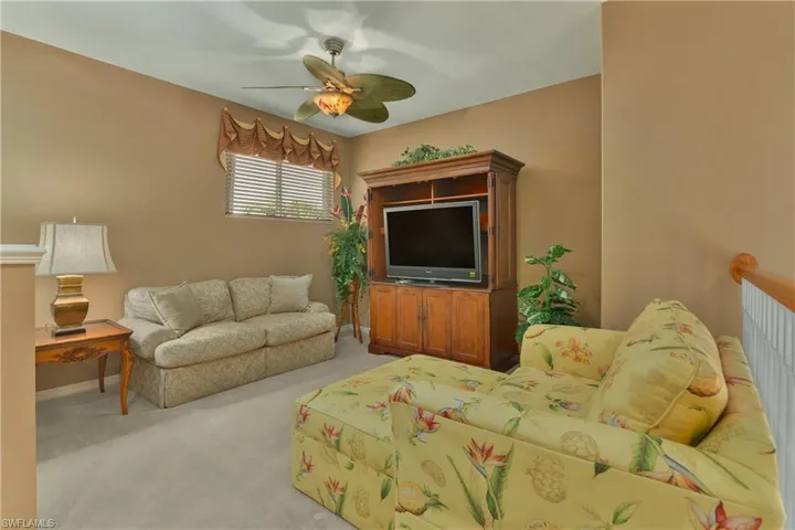 Living area with light colored carpet and a ceiling fan