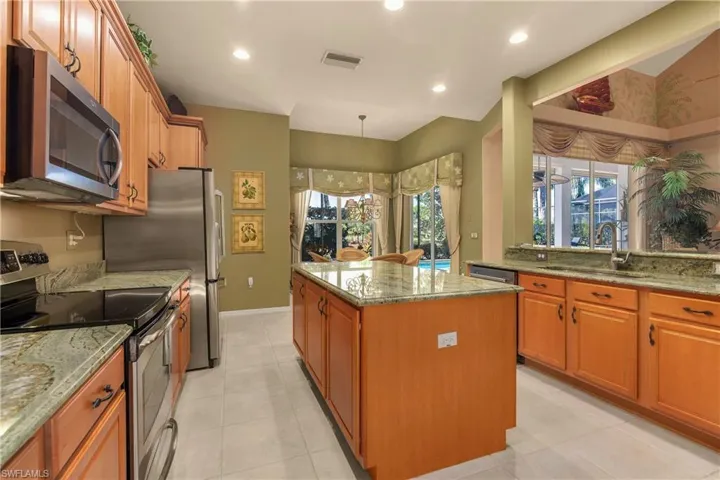 Kitchen featuring stainless steel appliances, light stone counters, a kitchen island, pendant lighting, and recessed lighting
