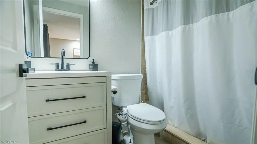 Bathroom with a textured wall, vanity, and a stall shower