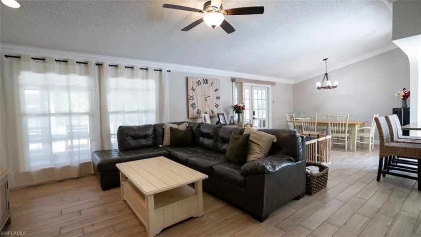 Living area featuring a ceiling fan, crown molding, wood finish floors, and hanging lights