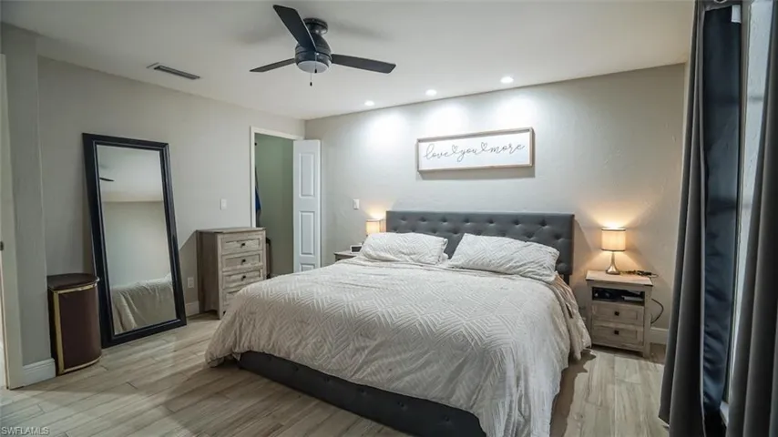 Bedroom with light wood-type flooring, ceiling fan, recessed lighting, and a textured wall