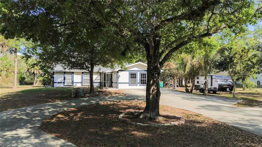 View of front facade featuring curved driveway and a front yard