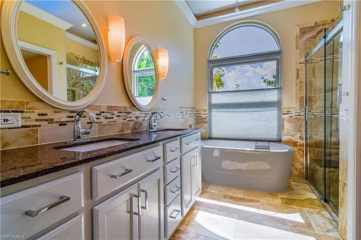 Primary En Suite bathroom featuring stand alone soaking tub and faucet, walk in shower, crown molding, dual vanity, LED ambient lighting.