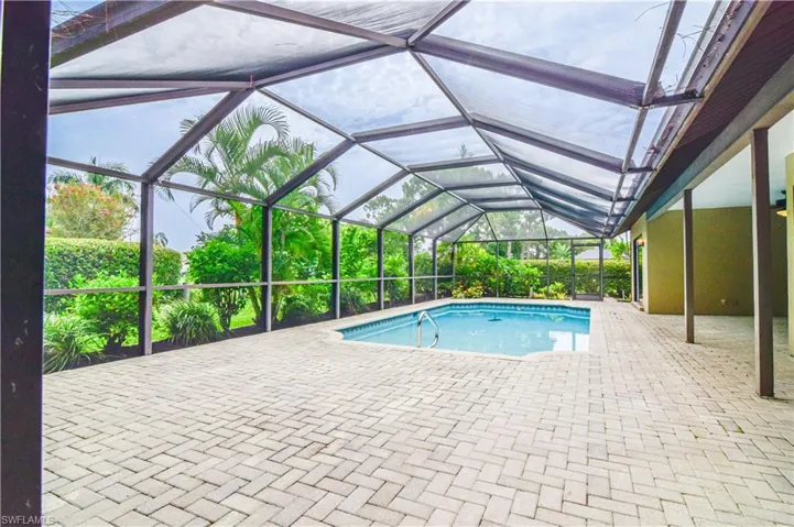 View of swimming pool with a patio and screen enclosure.