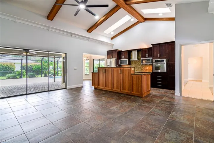 Timeless kitchen with a skylight, ceiling fan, high vaulted ceiling, and stainless steel appliances.