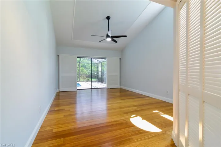 Primary Bedroom with banboo flooring, ceiling fan, and vaulted ceiling