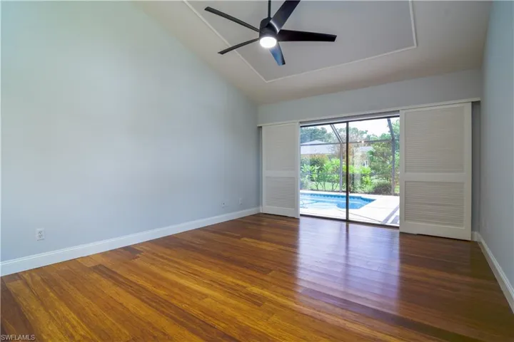 Primary bedroom overlooking swimming pool though double slider framed by plantation shutters.