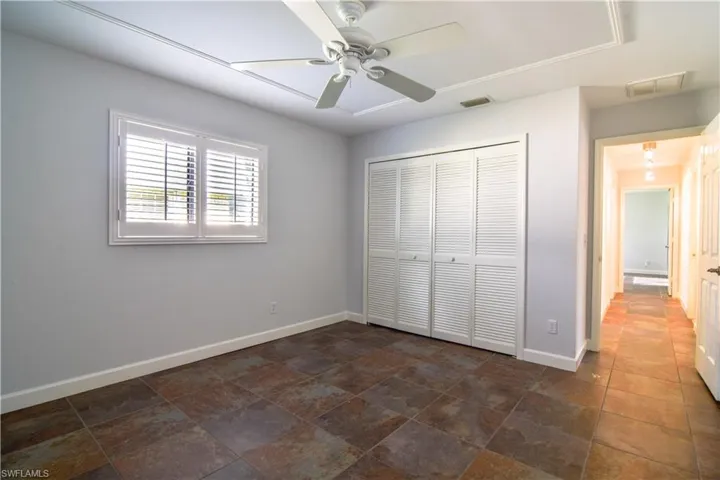Guest bedroom #1 with plantation shutters & ceiling fan.