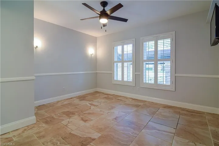 Guest bedroom #3 with lighted wall sconces, impact glass windows & plantation shutters.