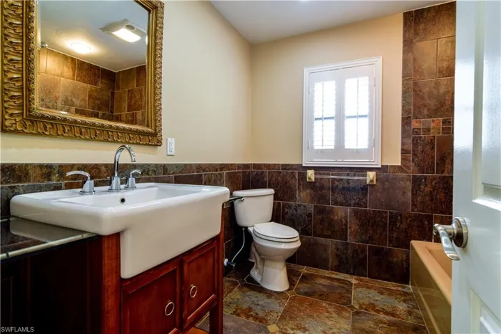 Guest Bathroom featuring tile flooring & walls, toilet, vanity, and shower/tub combination.
