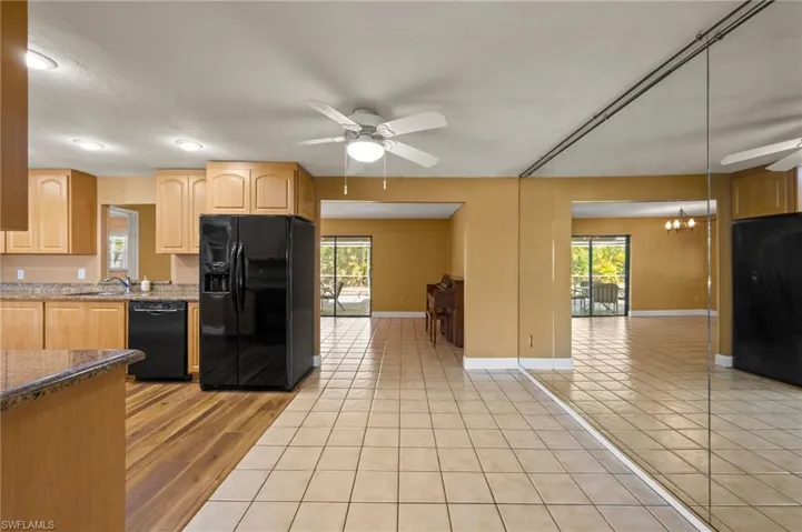 Kitchen featuring black appliances, ceiling fan with notable chandelier, a healthy amount of sunlight, and light tile patterned floors