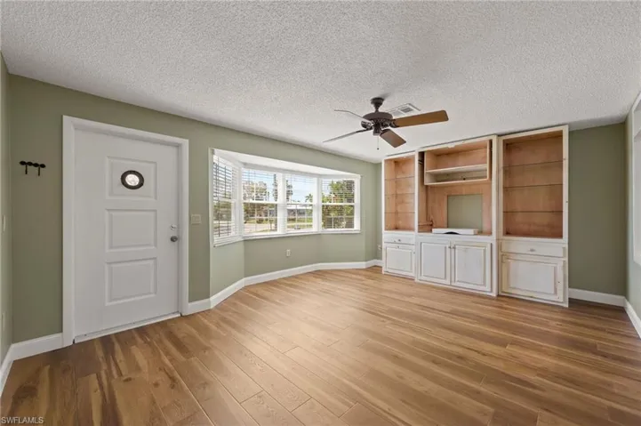 Unfurnished living room featuring ceiling fan, light hardwood / wood-style floors, and a textured ceiling
