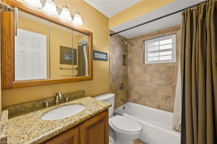 Full bathroom featuring vanity, shower / bathtub combination with curtain, and toilet
