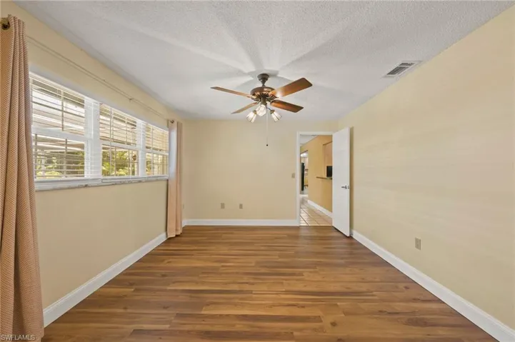 Empty room with a textured ceiling, ceiling fan, and dark wood-type flooring