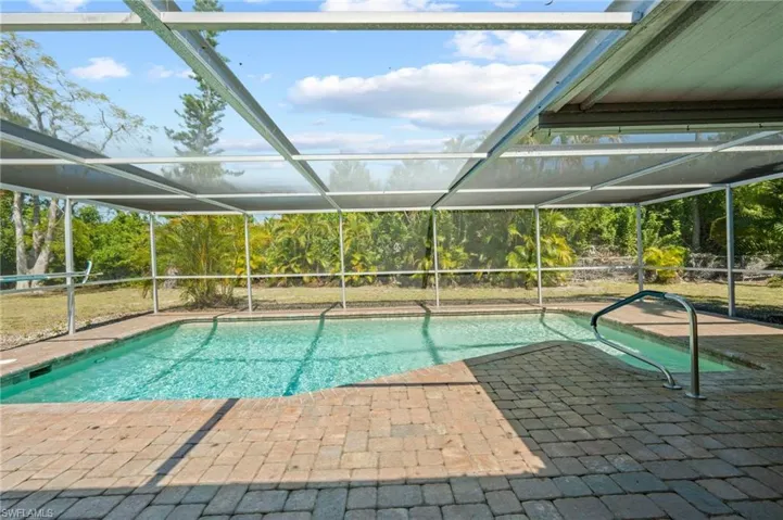 View of swimming pool with glass enclosure and a patio