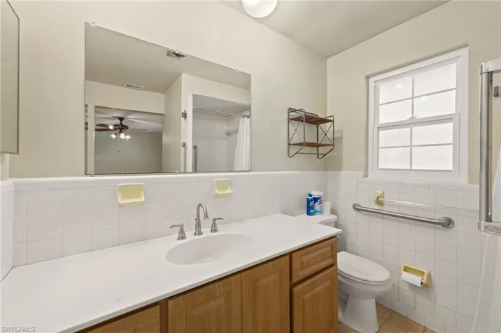 Bathroom featuring vanity, ceiling fan, tile walls, tile patterned flooring, and toilet