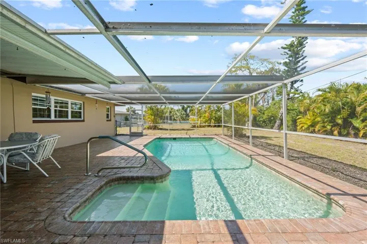 View of pool with glass enclosure and a patio