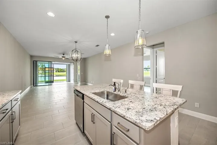 Kitchen featuring ceiling fan, pendant lighting, stainless steel dishwasher, sink, and an island with sink