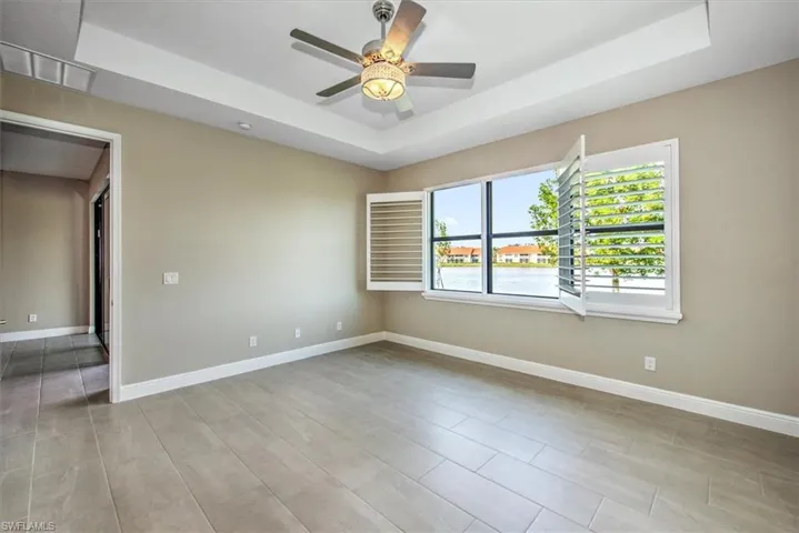 Featuring ceiling fan, a water view, and a tray ceiling