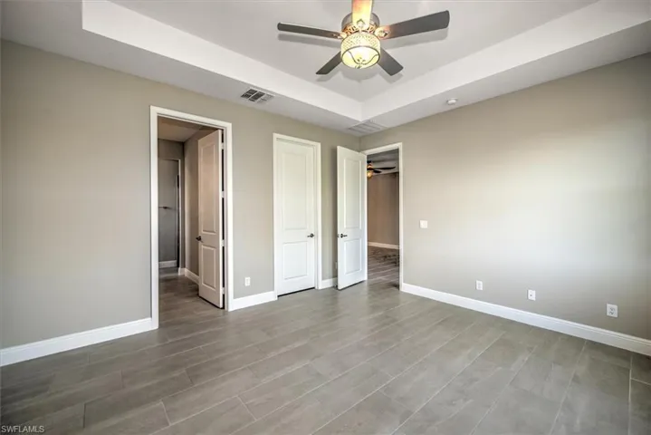 Unfurnished bedroom featuring ceiling fan and a raised ceiling