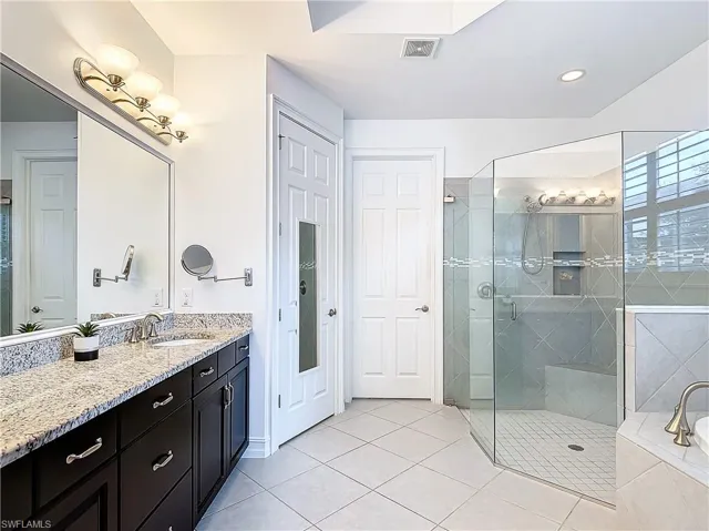 Bathroom featuring a shower with shower door, vanity, and tile patterned flooring