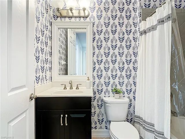 Full bathroom with vanity, shower / bath combo with shower curtain, and toilet