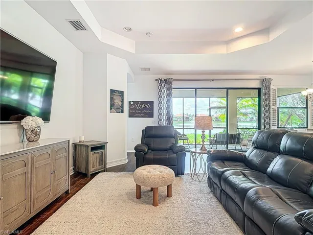 Living room featuring an inviting chandelier, dark hardwood / wood-style floors, and a tray ceiling