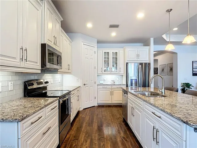 Kitchen featuring appliances with stainless steel finishes, dark hardwood / wood-style flooring, white cabinetry, and backsplash