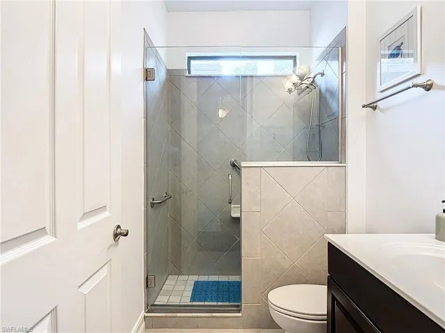 Bathroom featuring vanity, toilet, walk in shower, and tile walls