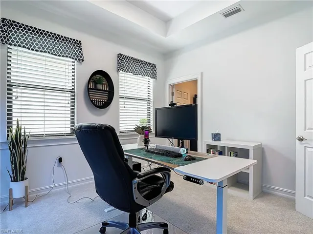 Home office with light carpet and a raised ceiling