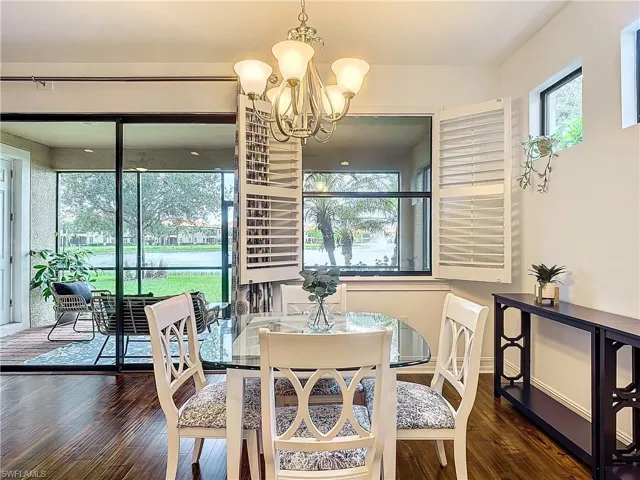 Dining area featuring an inviting chandelier, a wealth of natural light, and dark wood-type flooring