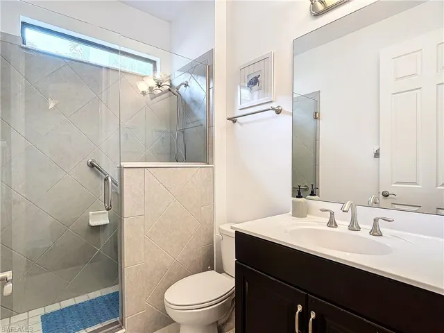 Bathroom featuring a shower with shower door, vanity, and toilet