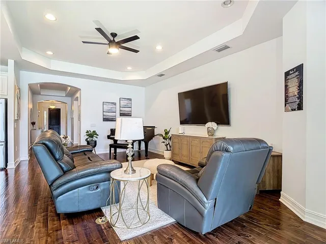 Living room featuring dark hardwood / wood-style floors, a raised ceiling, and ceiling fan