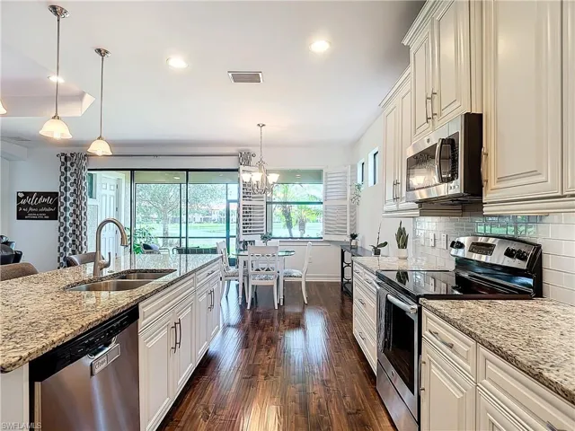 Kitchen featuring tasteful backsplash, sink, light stone counters, dark hardwood / wood-style floors, and appliances with stainless steel finishes