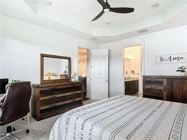 Bedroom featuring connected bathroom, ceiling fan, and a raised ceiling