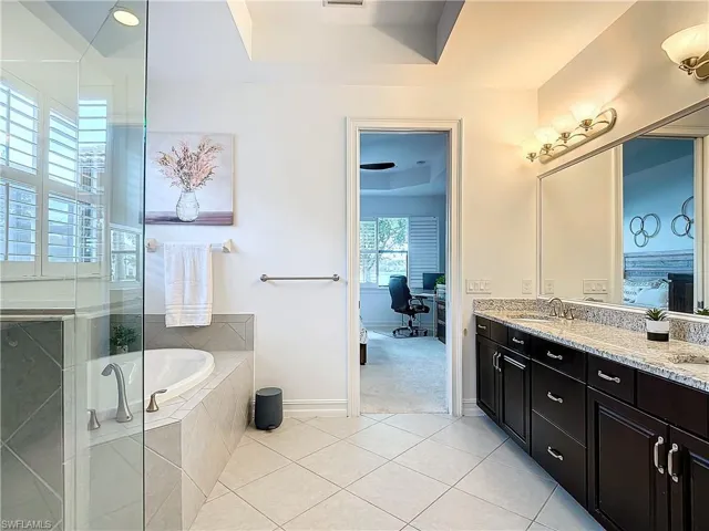 Bathroom featuring double vanity, plus walk in shower, tile patterned flooring, and a tray ceiling