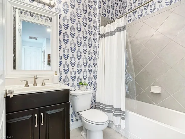 Full bathroom with vanity, shower / tub combo, toilet, and tile patterned flooring